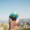 person holding world globe facing mountain